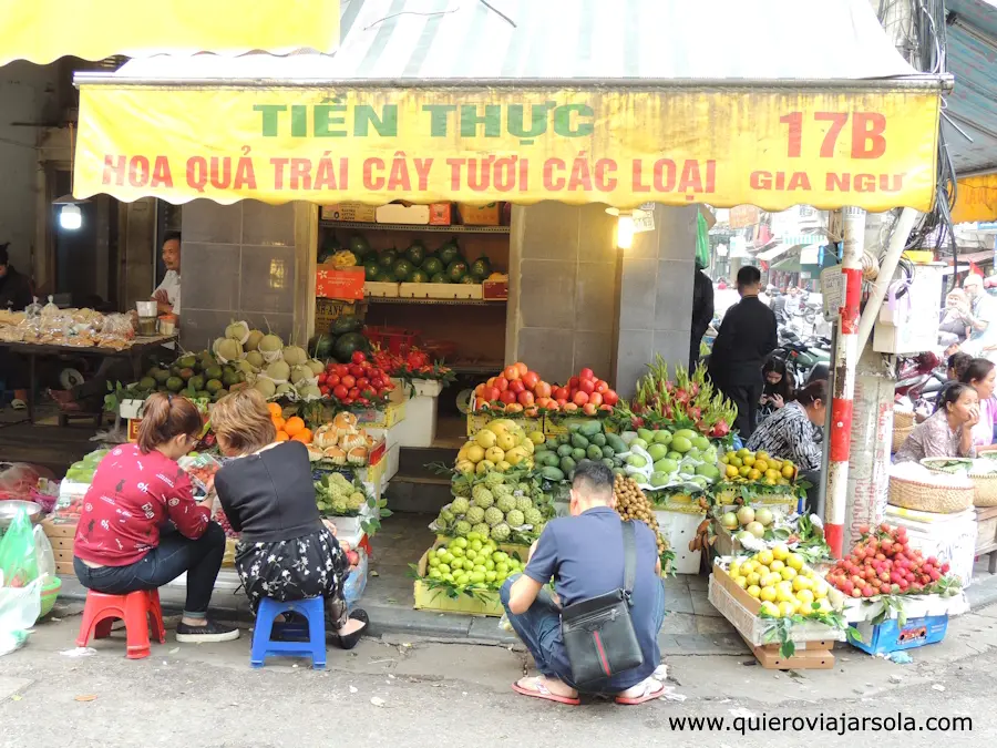 Gente en una tienda de Hanoi con la acera ocupada de productos a la venta