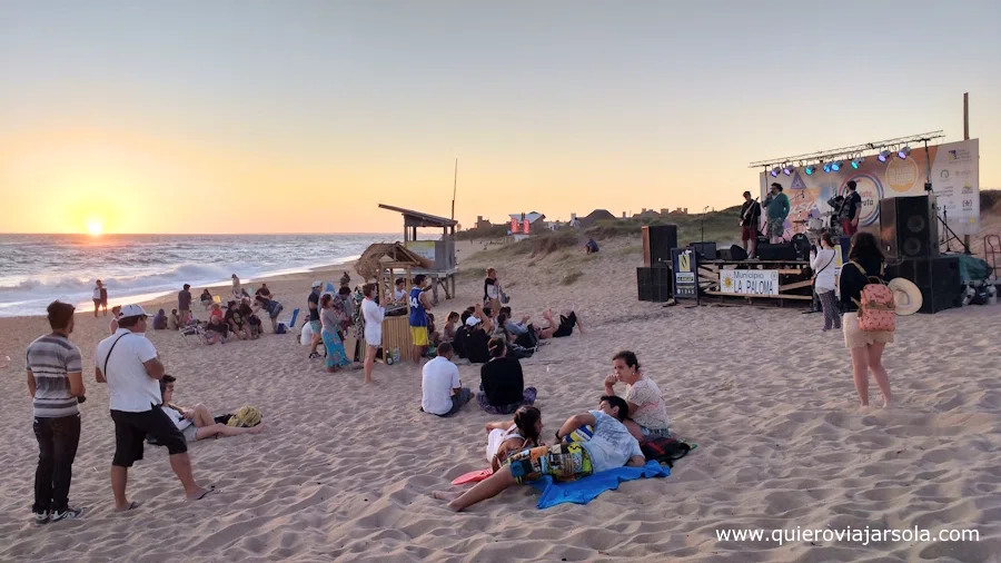Gente disfrutando de un concierto en la playa al atardecer