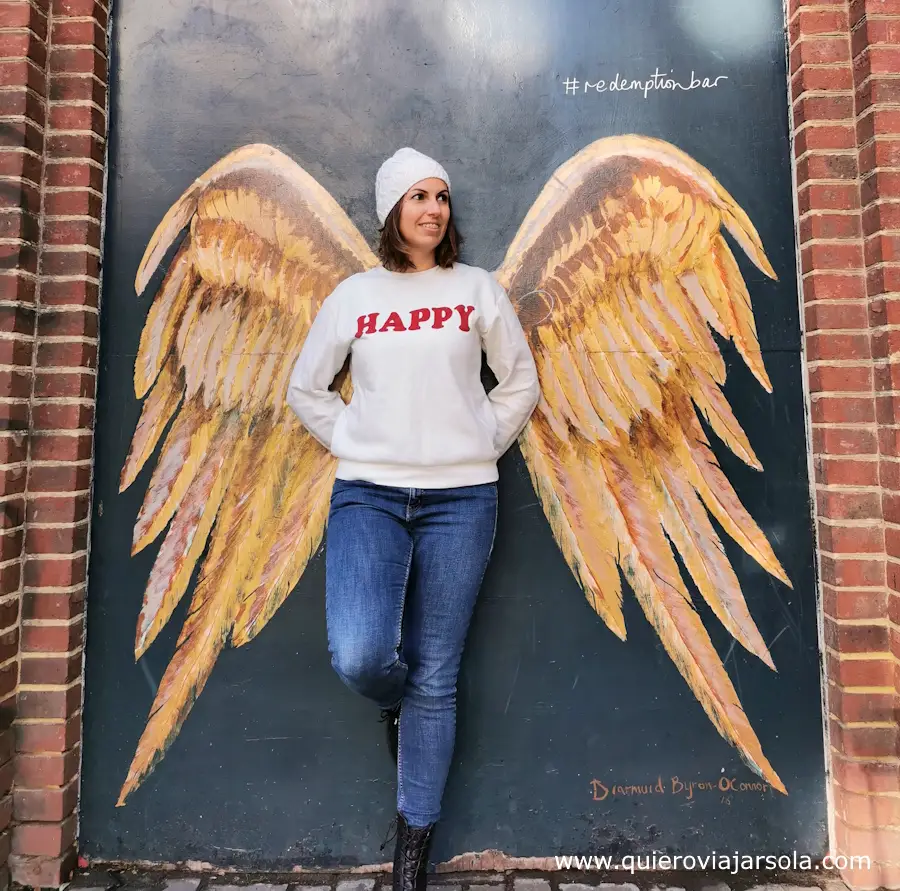 Yo posando en una pared con alas pintadas