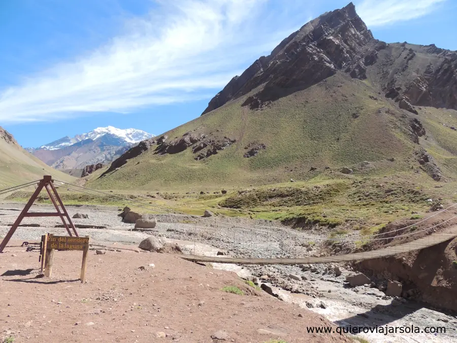 Paisaje de montaña con un pequeño puente y el cerro Aconcagua de fondo