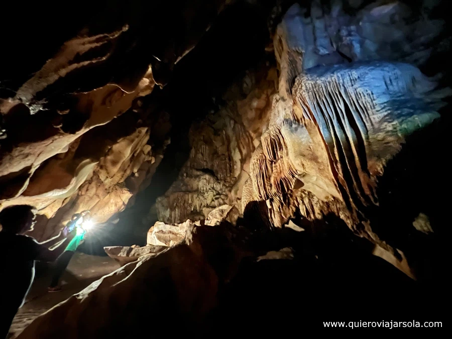 Interior de la cueva oscura con la guía iluminando con la linterna