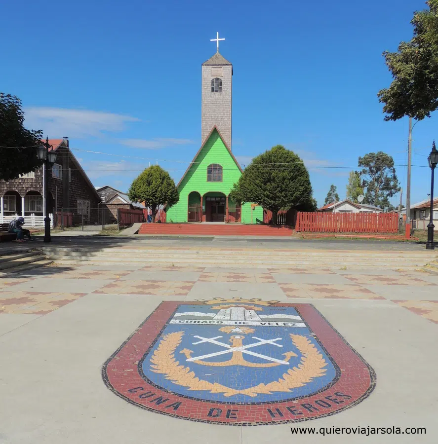 Escudo de Curaco en la plaza con la iglesia de fondo